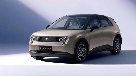 En beige kompakt SUV med runde forlygter og sorte detaljer er parkeret i et studie med lysegrå baggrund. På den forreste nummerplade står der FIREFLY.